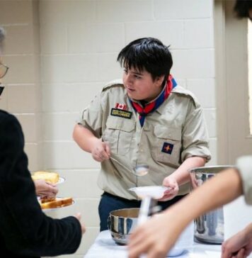 Serving with Joy: Explorers and Seniors Unite at St. Thomas the Apostle Parish A young explorer serves senior parishioners in a Church hall