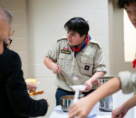 Serving with Joy: Explorers and Seniors Unite at St. Thomas the Apostle Parish A young explorer serves senior parishioners in a Church hall