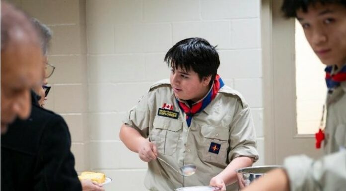 Serving with Joy: Explorers and Seniors Unite at St. Thomas the Apostle Parish A young explorer serves senior parishioners in a Church hall